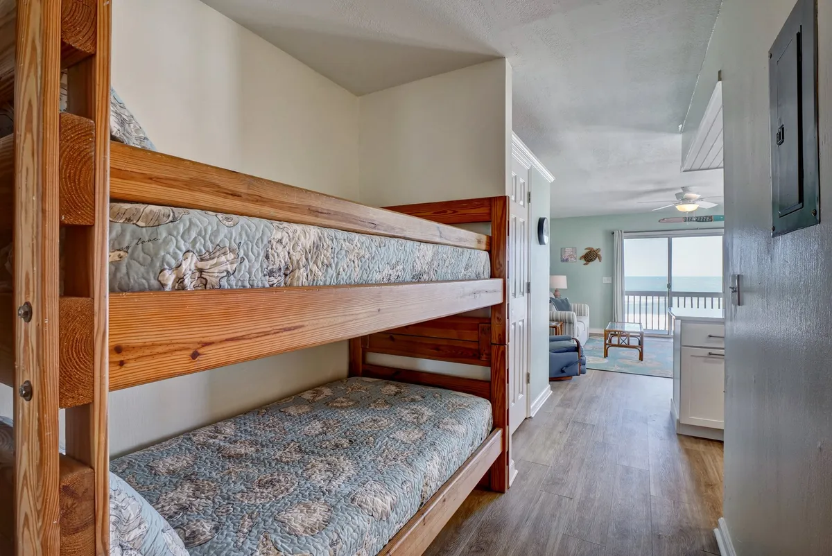A cozy hallway nook with twin-over-twin bunk beds and an open doorway leading to the living area. The space is playful yet snug, ideal for kids or friends, with morning light spilling into the room.