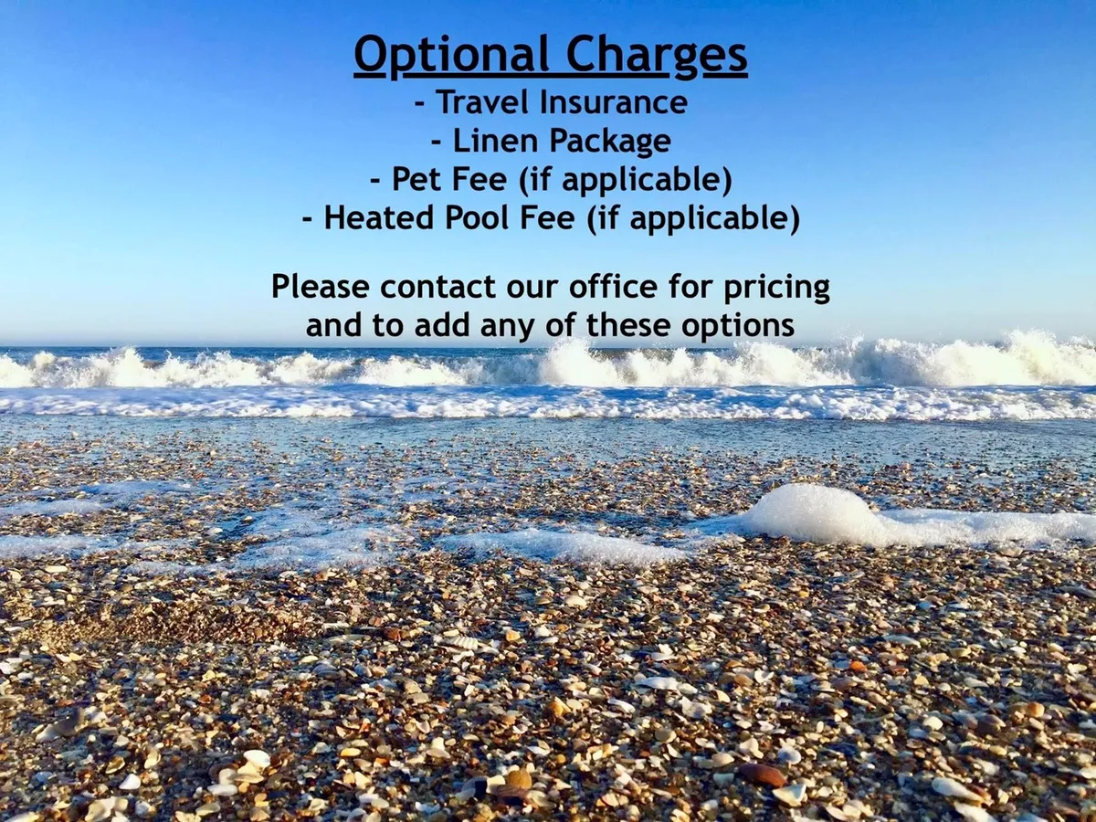 A scenic view of a sandy beach meeting gentle waves under a clear blue sky. The tranquil shoreline is perfect for family activities like swimming, sunbathing, and beachcombing, and evokes the quintessential beach vacation setting, just steps away from the property.