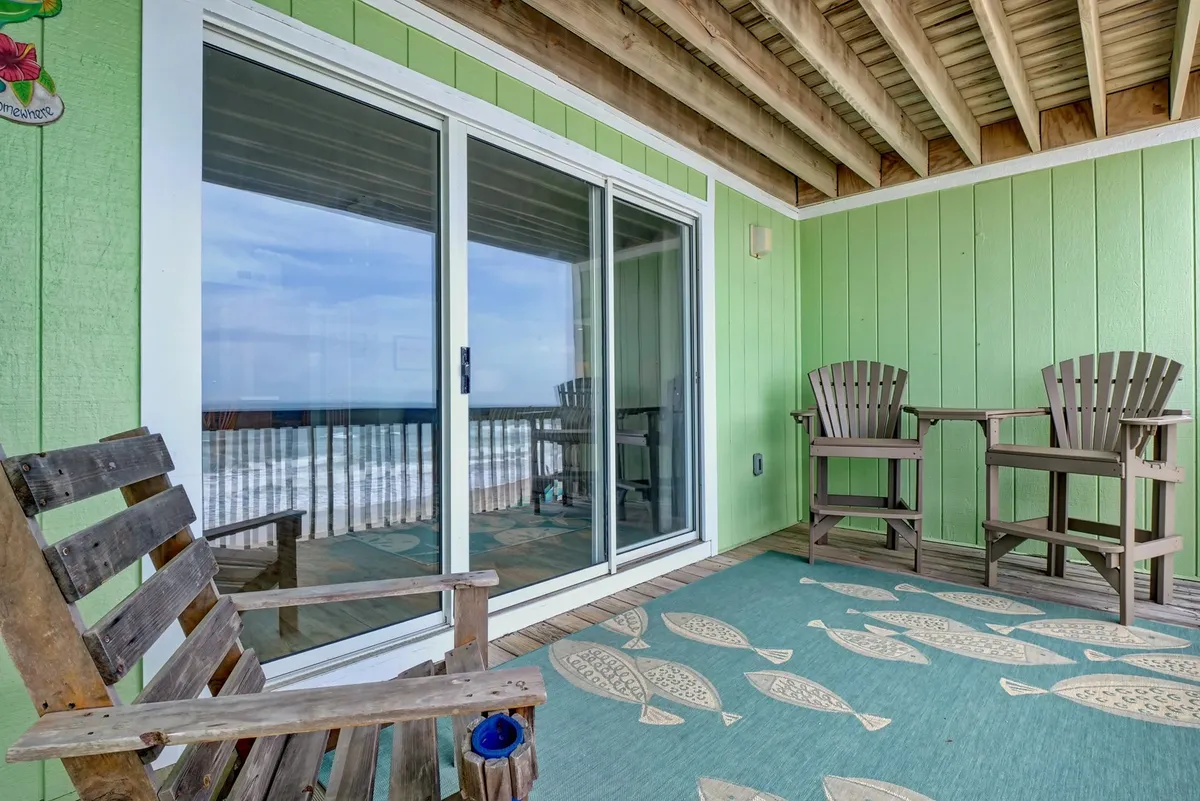 A serene patio setup featuring comfortable chairs, a decorative rug, and a sweeping ocean view. The scene is perfect for enjoying a drink or watching the sunrise, framed by the gentle blues of the Atlantic and a sense of privacy and tranquility.